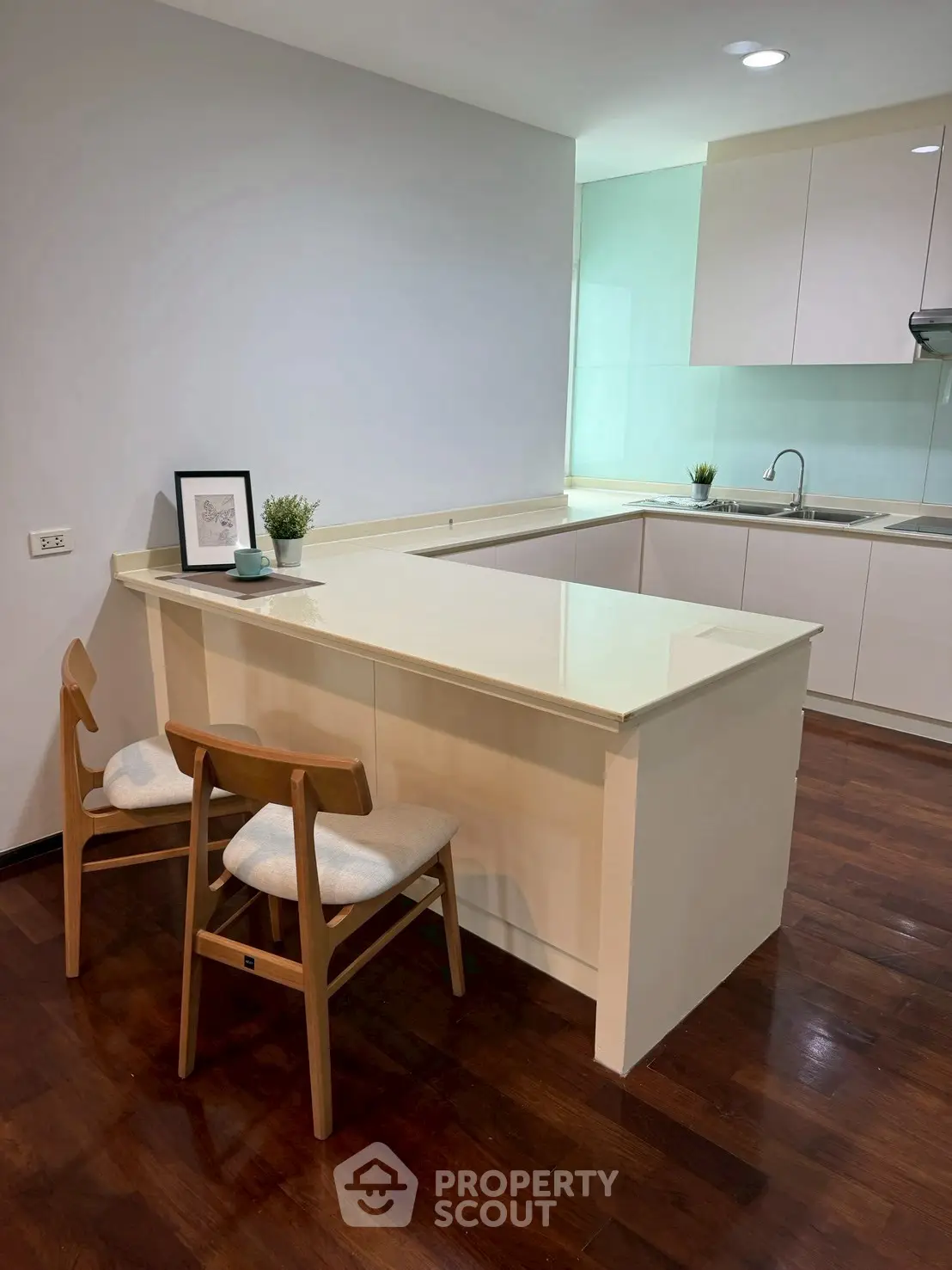Modern kitchen with sleek white cabinets and breakfast bar in a cozy apartment.