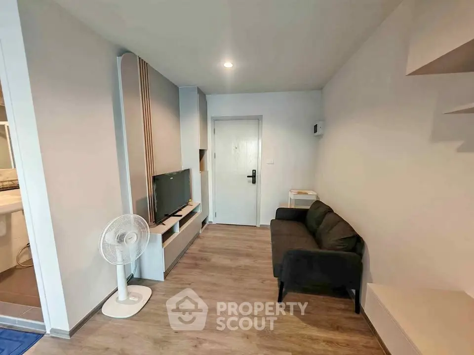 Modern living room with sleek design, featuring a cozy sofa, flat-screen TV, and stylish wooden flooring.