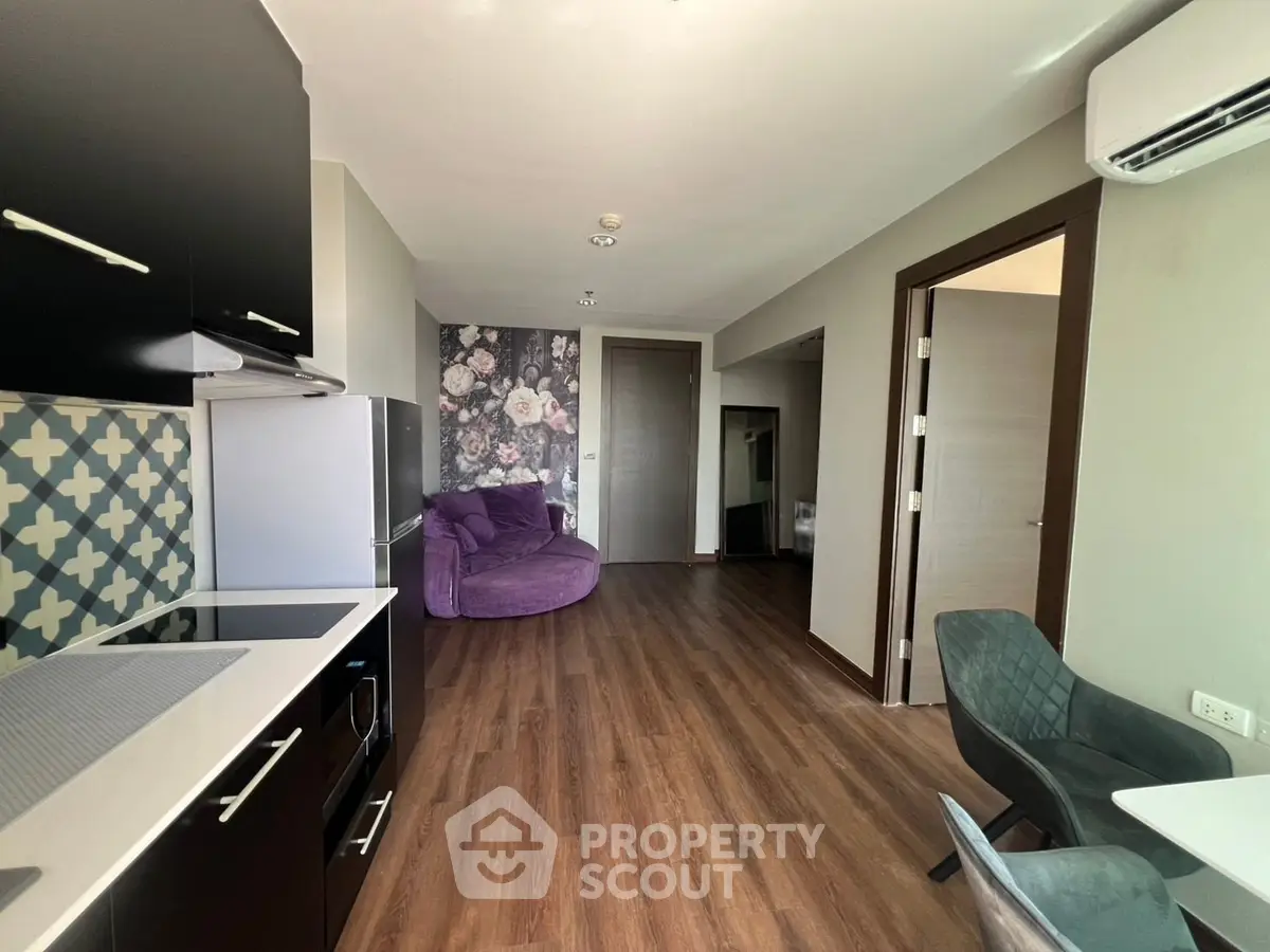 Modern apartment interior with stylish kitchen and cozy living area featuring floral accent wall.