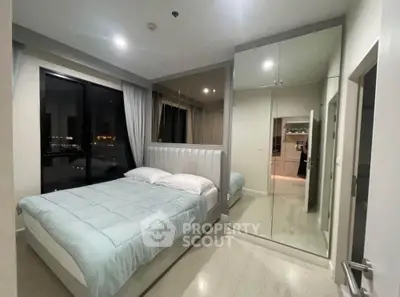 Modern bedroom with large mirror and city view window, featuring sleek design and cozy ambiance.
