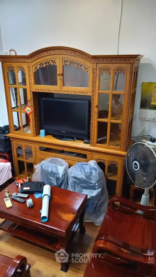 Elegant wooden living room furniture with intricate carvings and a TV setup, showcasing classic interior design.