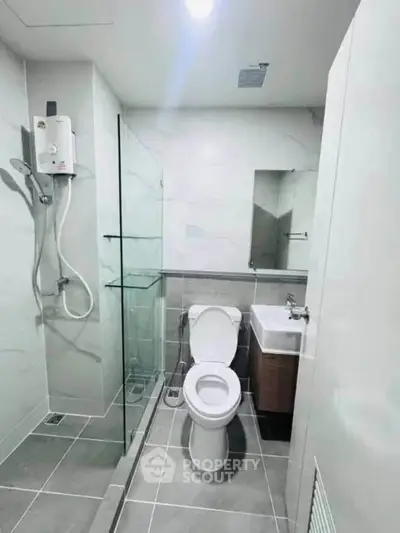 Modern bathroom with sleek design, featuring a glass shower enclosure and compact layout.