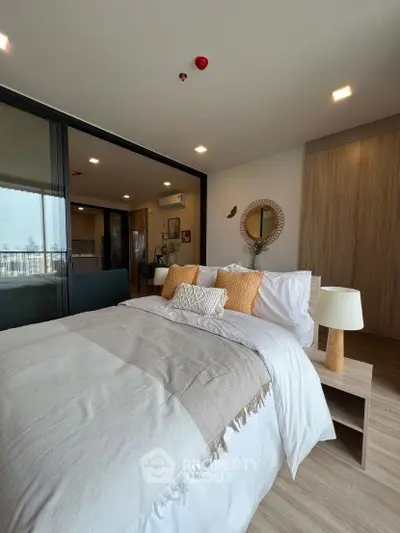 Spacious modern bedroom with cozy decor and sliding glass doors leading to a bright living area.
