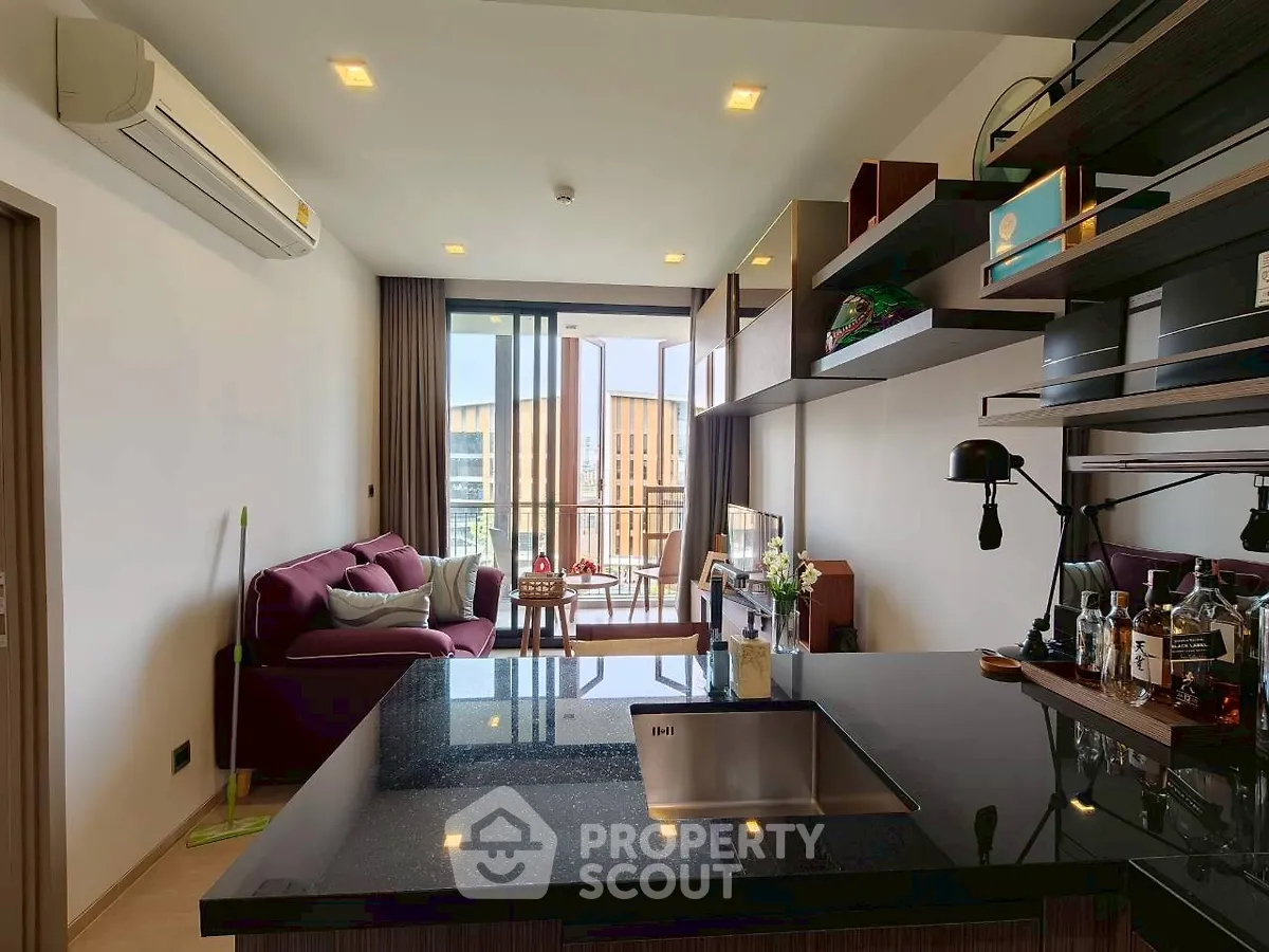 Modern open-plan living room with sleek kitchen and balcony view