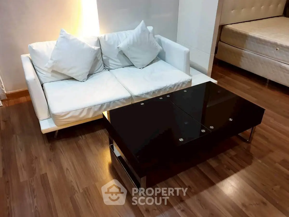 Modern living room with sleek black coffee table and white sofa on polished wooden floor.