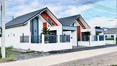 Modern single-story house with unique roof design and fenced yard.