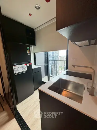 Modern kitchen with sleek black appliances and city view from balcony