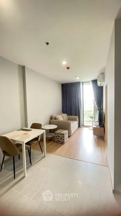 Modern living room with cozy sofa, dining table, and natural light from balcony.