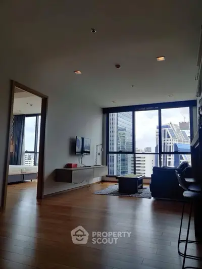 Modern living room with city view, wooden flooring, and stylish furniture in a high-rise apartment.