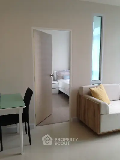 Modern apartment interior with open living room and glimpse of cozy bedroom.