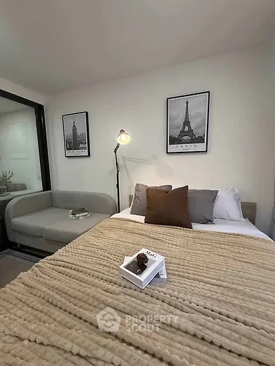 Cozy bedroom with modern decor and stylish artwork, featuring a comfortable bed and a chic sofa.