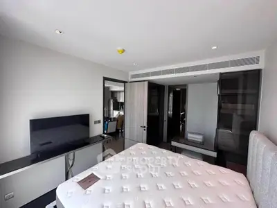 Modern bedroom with sleek furniture and large TV in a contemporary apartment.
