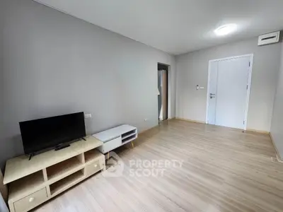 Spacious minimalist living room with wooden flooring and modern TV setup.