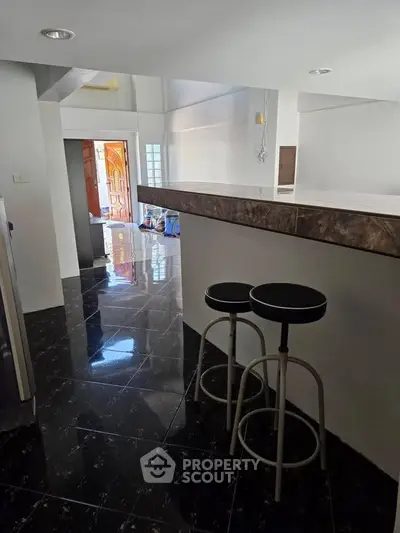 Spacious modern kitchen with sleek black flooring and breakfast bar