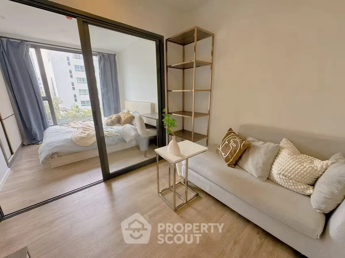 Modern apartment with cozy living room and bedroom separated by glass doors, featuring stylish decor.