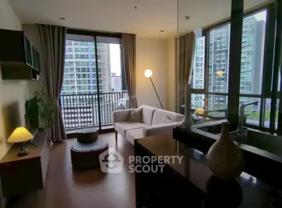 Modern living room with large windows and city view, featuring cozy seating and stylish decor.