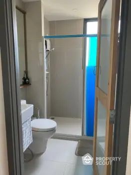 Modern bathroom with glass shower enclosure, sleek toilet design, and neutral color palette ensuring a clean, minimalist aesthetic.