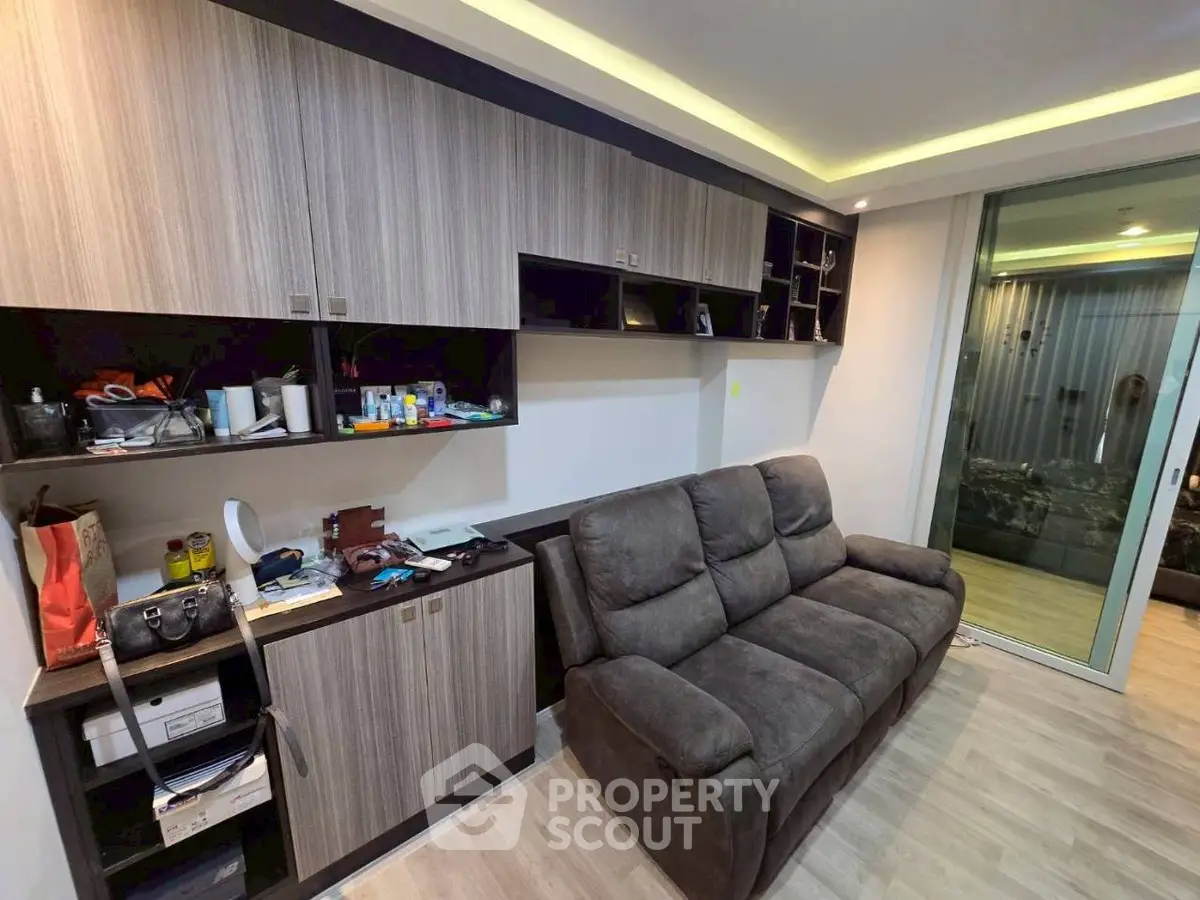 Modern living room with sleek cabinetry and cozy seating, featuring a sliding glass door to a balcony.