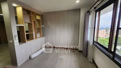 Spacious room with large window and built-in shelving, offering a bright and airy atmosphere.