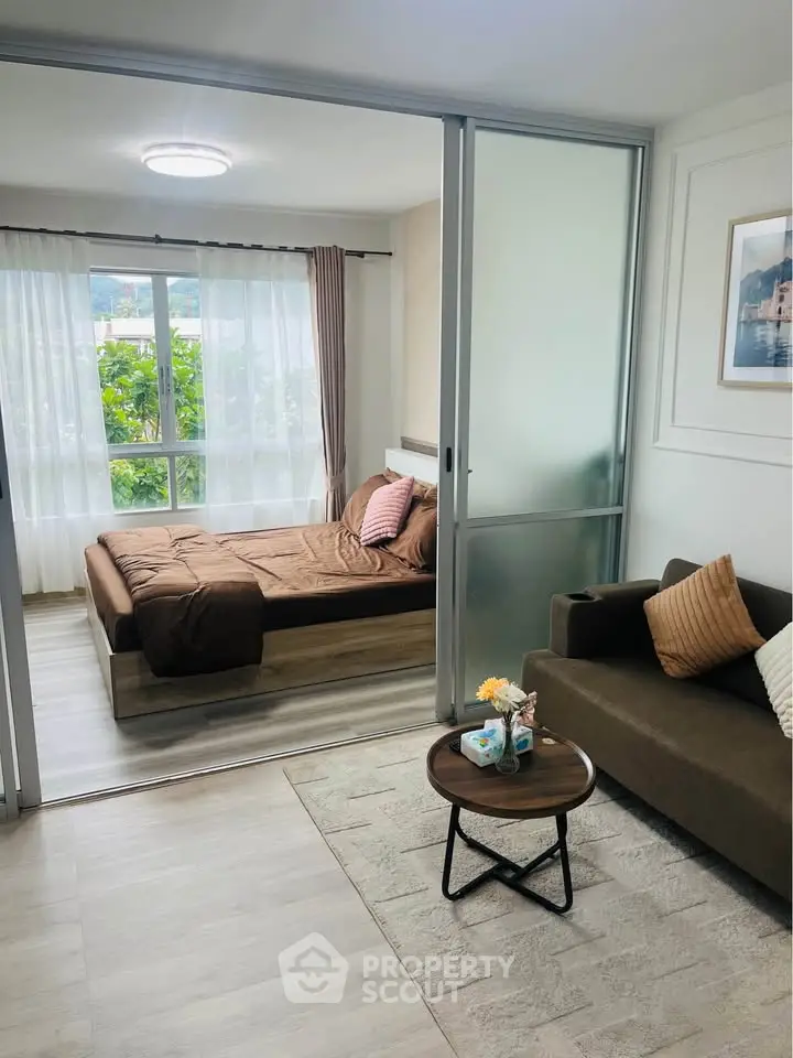 Modern studio apartment with sliding glass doors separating bedroom and living area, featuring cozy decor.