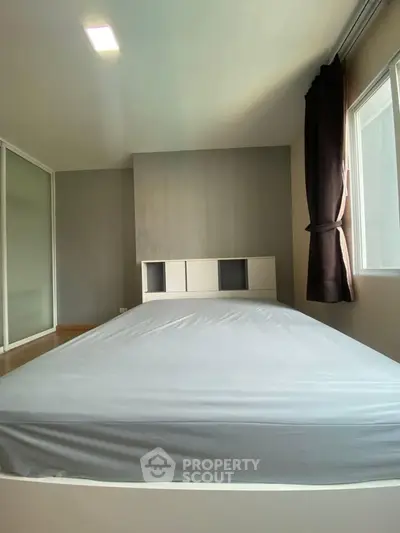 Spacious bedroom with large window and modern design in a well-lit apartment.