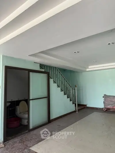 Spacious interior with staircase and adjacent bathroom, ideal for renovation.