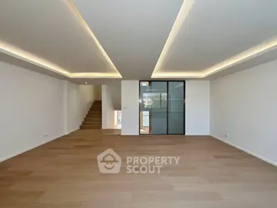 Spacious modern living room with sleek wooden flooring and stylish ceiling lights.