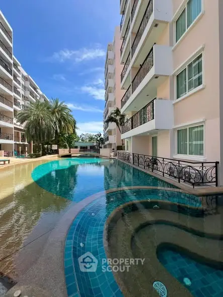 Luxurious apartment complex with stunning pool and palm trees under clear blue sky.