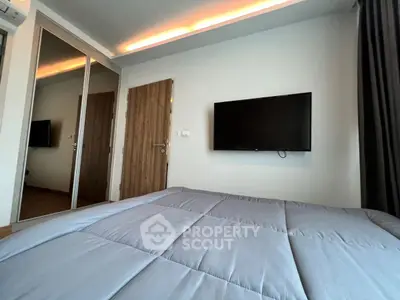 Modern bedroom with wall-mounted TV and mirrored closet doors