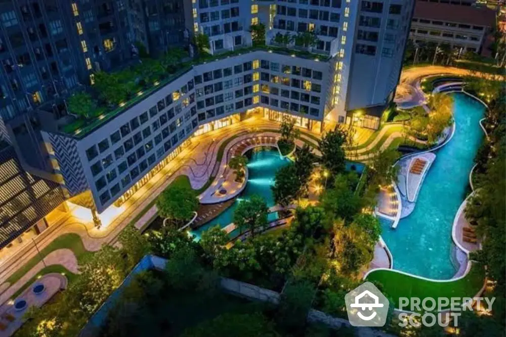 Luxurious urban residential complex with stunning night view of illuminated pool and lush gardens.