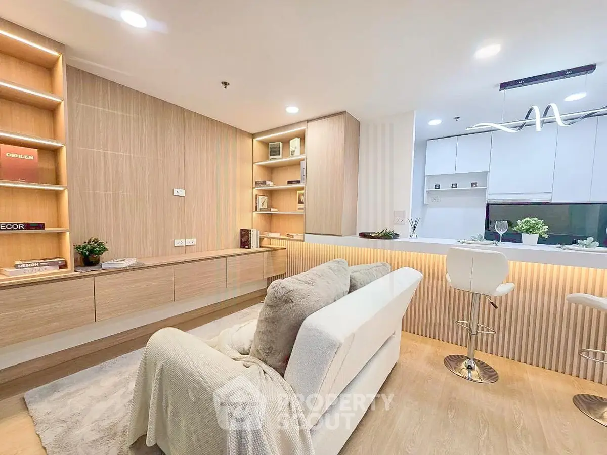 Modern living room with open kitchen, featuring sleek design and cozy ambiance.