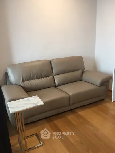 Modern living room with sleek leather sofa and elegant side table on wooden flooring.