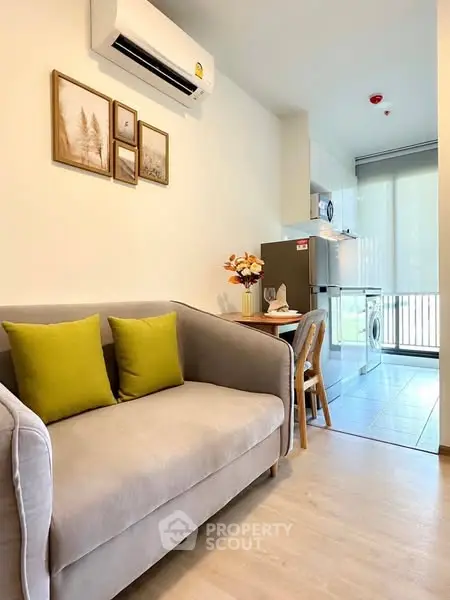 Cozy living room with modern sofa, dining area, and compact kitchen in a stylish apartment.