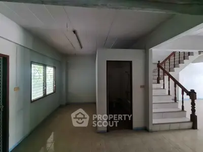 Spacious interior with staircase and natural light, ideal for renovation.