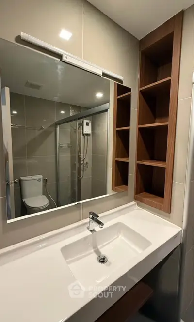 Modern bathroom with sleek sink, mirror, and shower area in contemporary design.