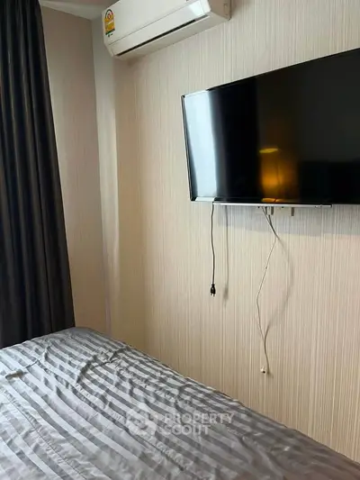Modern bedroom with wall-mounted TV and air conditioning unit, featuring sleek design and cozy ambiance.