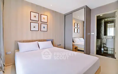 Modern bedroom with elegant decor and mirrored wardrobe in a stylish apartment.