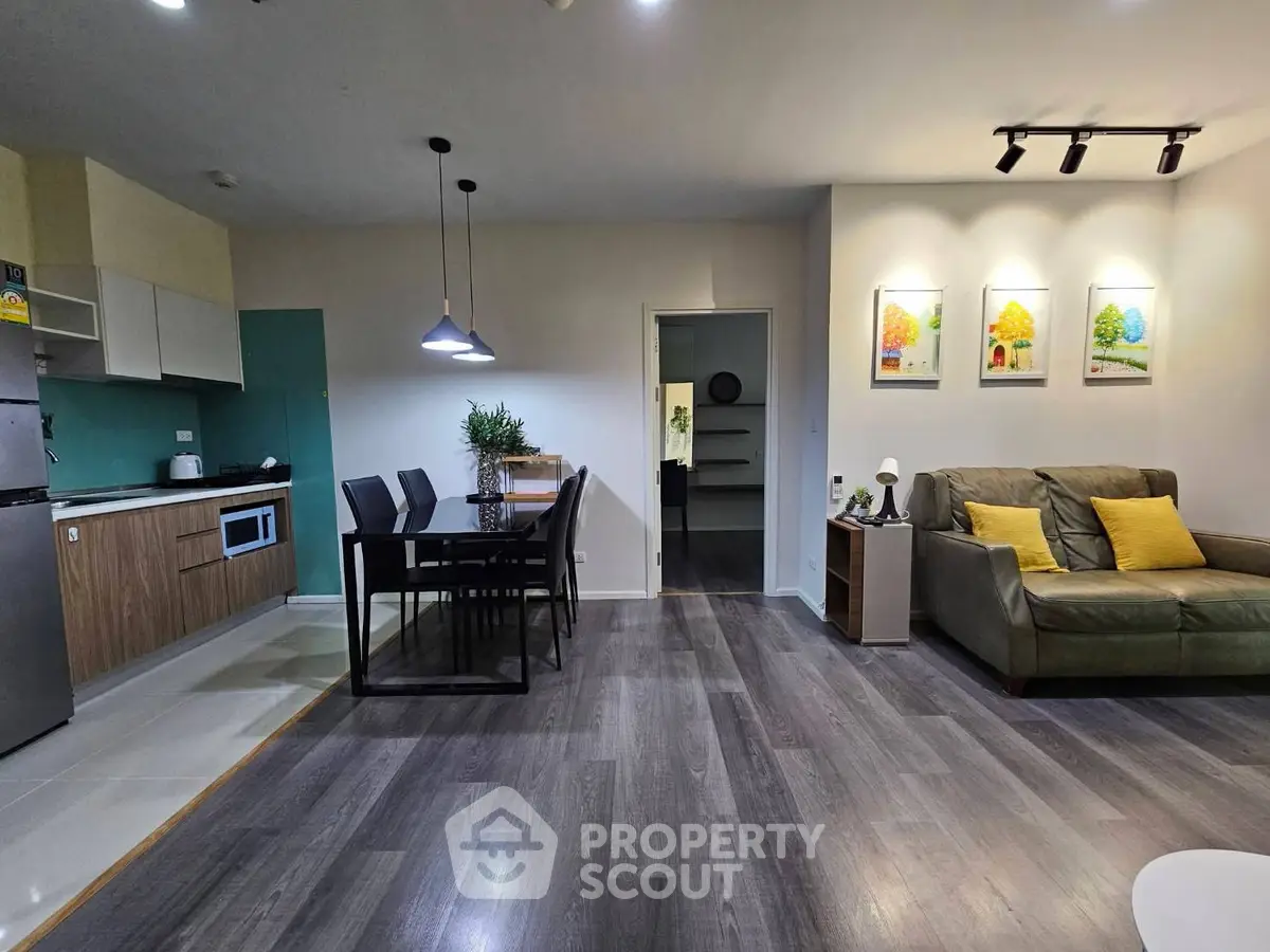 Modern open-plan living room with stylish kitchen and dining area, featuring sleek furniture and elegant decor.