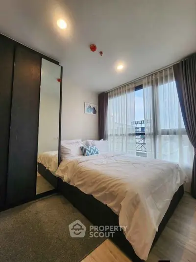 Modern bedroom with large window and stylish decor in a contemporary apartment.