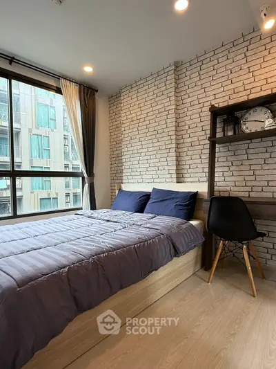 Modern bedroom with exposed brick wall and large window in urban apartment
