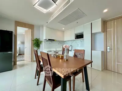 Modern kitchen with dining area, sleek cabinetry, and elegant decor in a bright, open space.