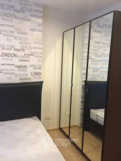 Modern bedroom with mirrored wardrobe and city-themed wallpaper, perfect for urban living.