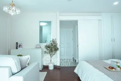 Elegant bedroom with modern decor and cozy seating area, featuring a sliding door and stylish lighting.