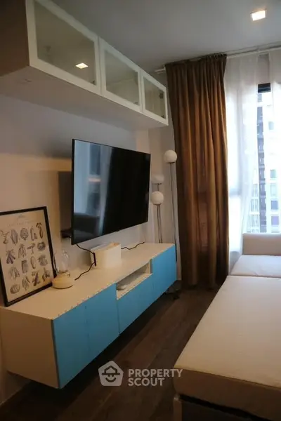 Modern living room with sleek TV setup and stylish decor in urban apartment.