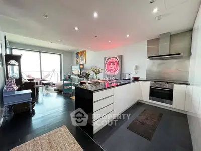 Modern open-plan kitchen with sleek design and spacious living area, featuring contemporary art and natural light.