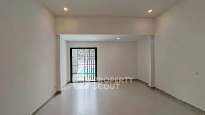 Spacious empty living room with large window overlooking pool area, perfect for modern living.