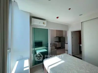 Modern bedroom with air conditioning and sliding glass doors leading to a compact kitchen area.