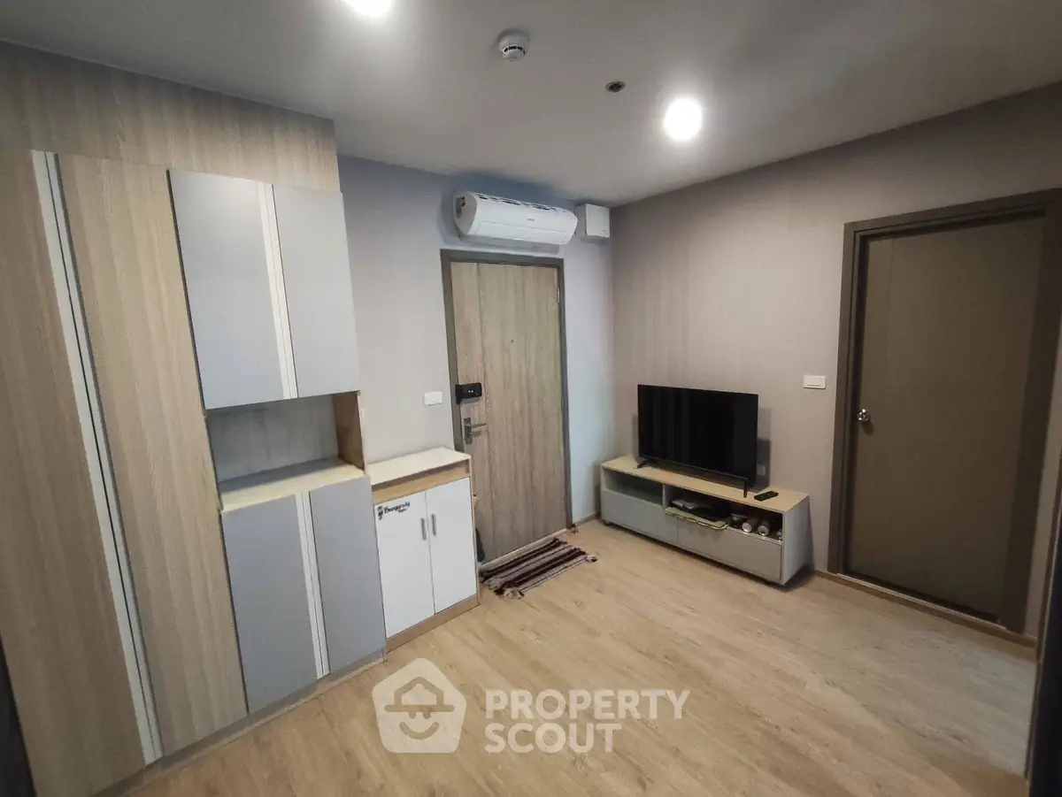 Modern living room with sleek design, featuring built-in storage and a flat-screen TV.