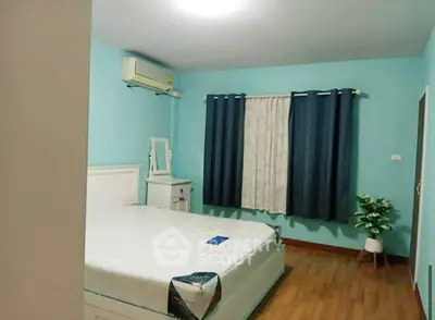 Cozy bedroom with blue walls, wooden flooring, and air conditioning, perfect for restful nights.