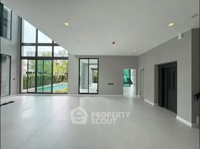 Spacious modern living room with floor-to-ceiling windows and pool view